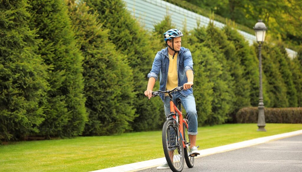 Young Man In Helmet Riding Bike Outdoors